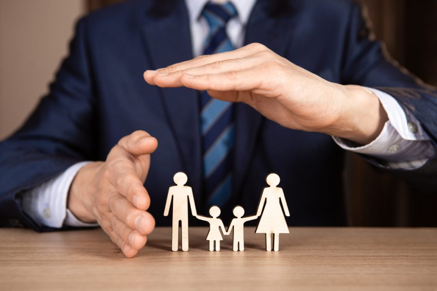 A man in a suit holds hands in the shape of a house over the family. Insurance concept. A man in a suit holds hands in the shape of a house over the family. Insurance concept.